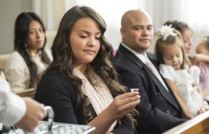 教会で聖餐の水をとる若い女性と家族