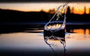 夕焼けを背景に、何かが水中に落ちて上がる水しぶき